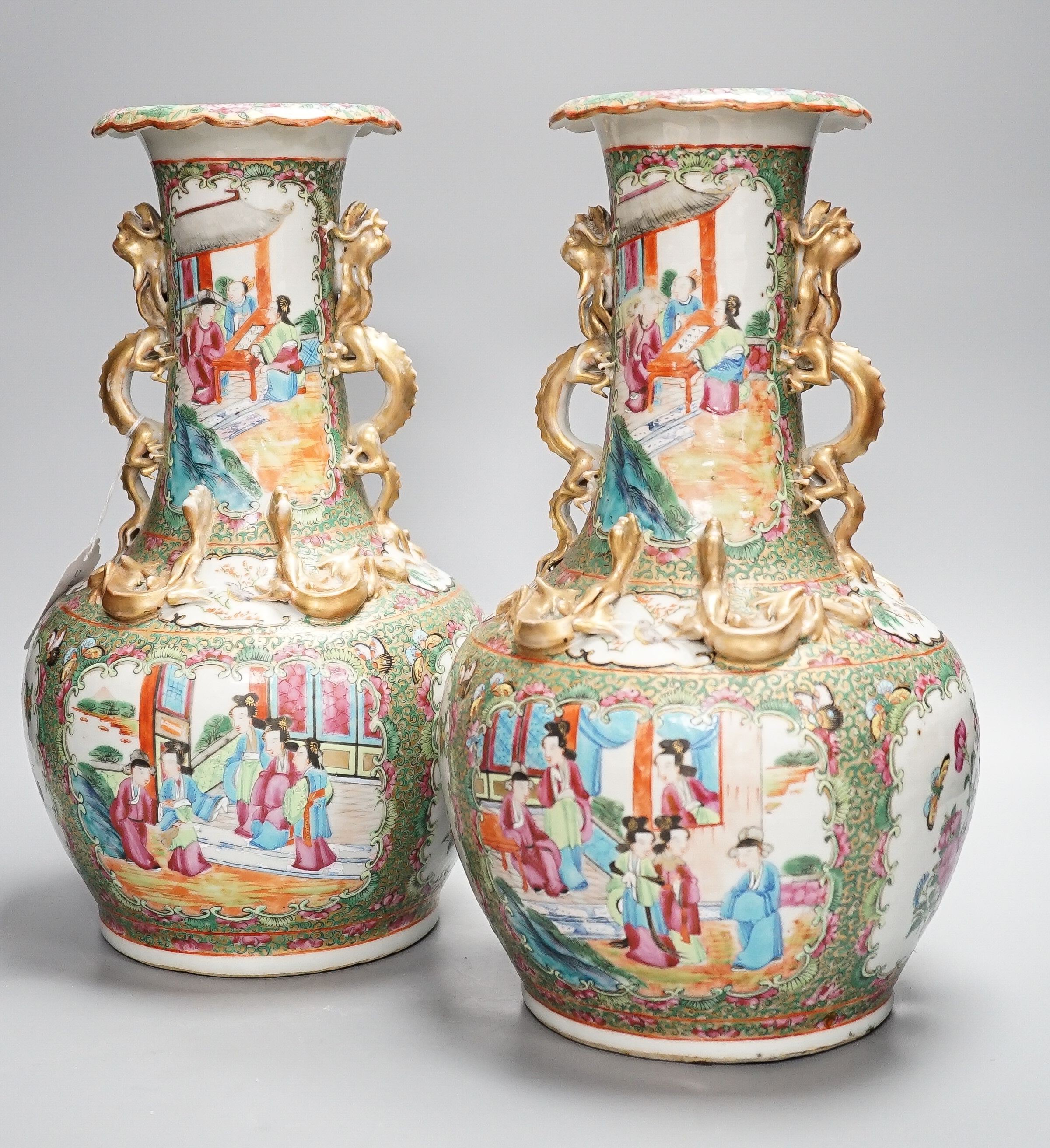 A pair of late 19th century Chinese famille rose vases, decorated with figures, birds and butterflies, twin lion dog handles, height 35cm